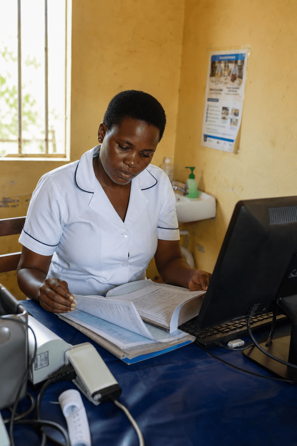 Nurse reviewing charts beside a clinic computer